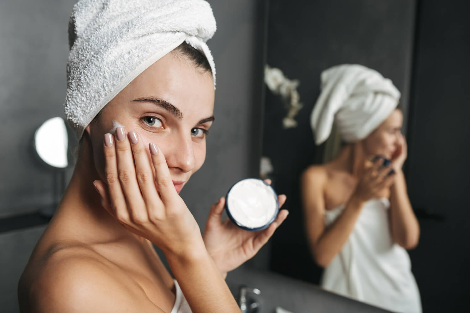 photo seductive woman wrapped towel applying cream face